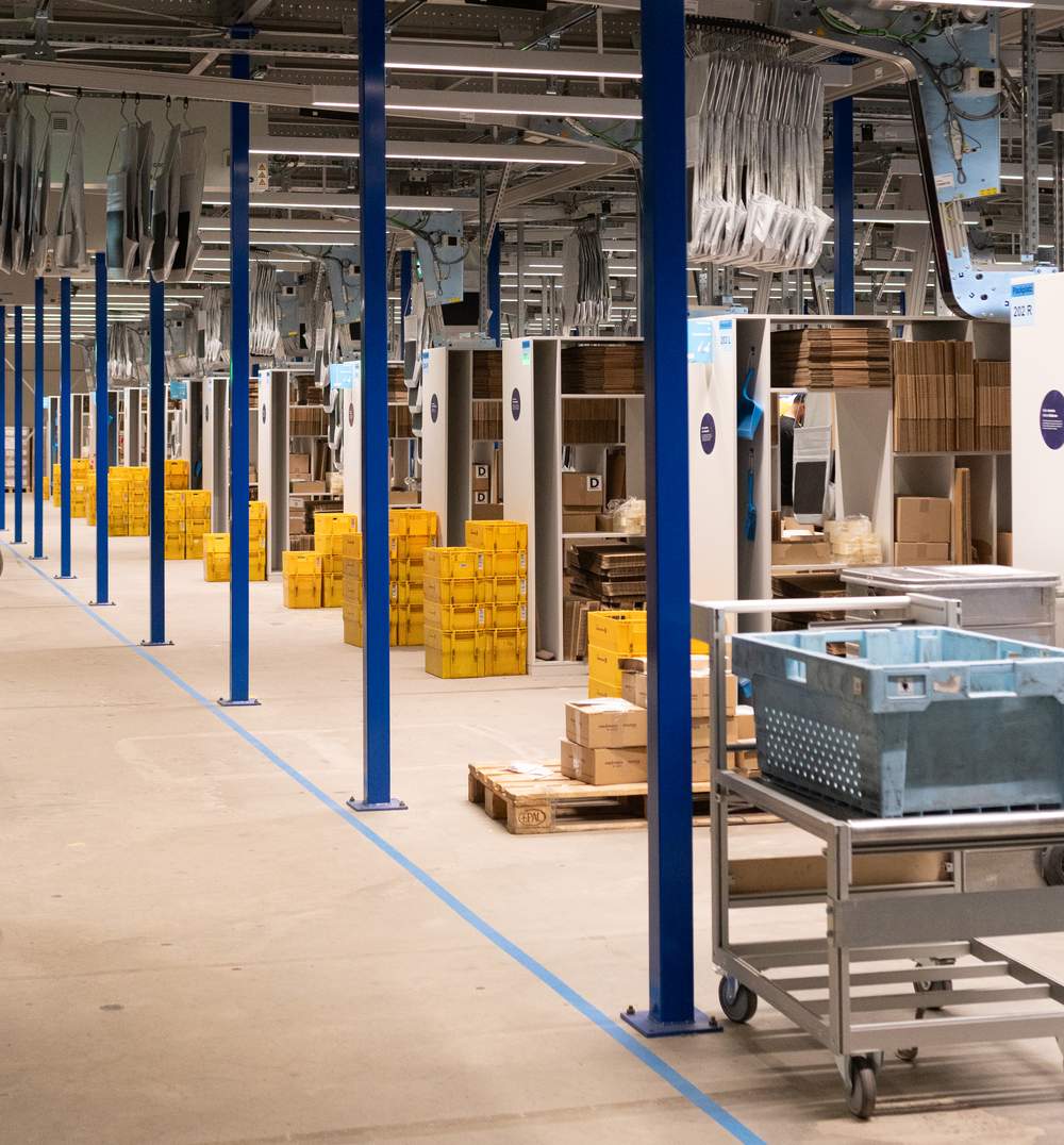 Neue Packplätze im momox-Lager Leipzig mit Kartonagen und gelben Behältern