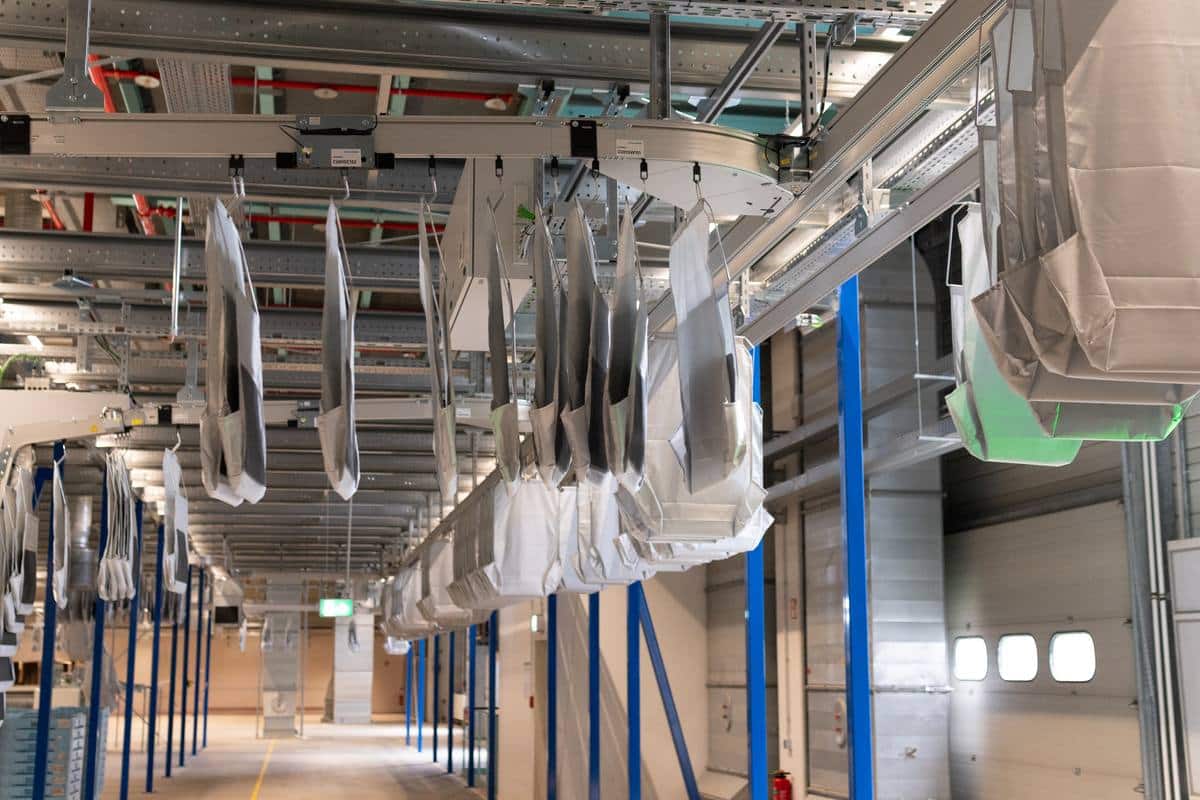 momox Taschensorter in Leipzig: Taschen hängen an der Förderbahn unter der Hallendecke