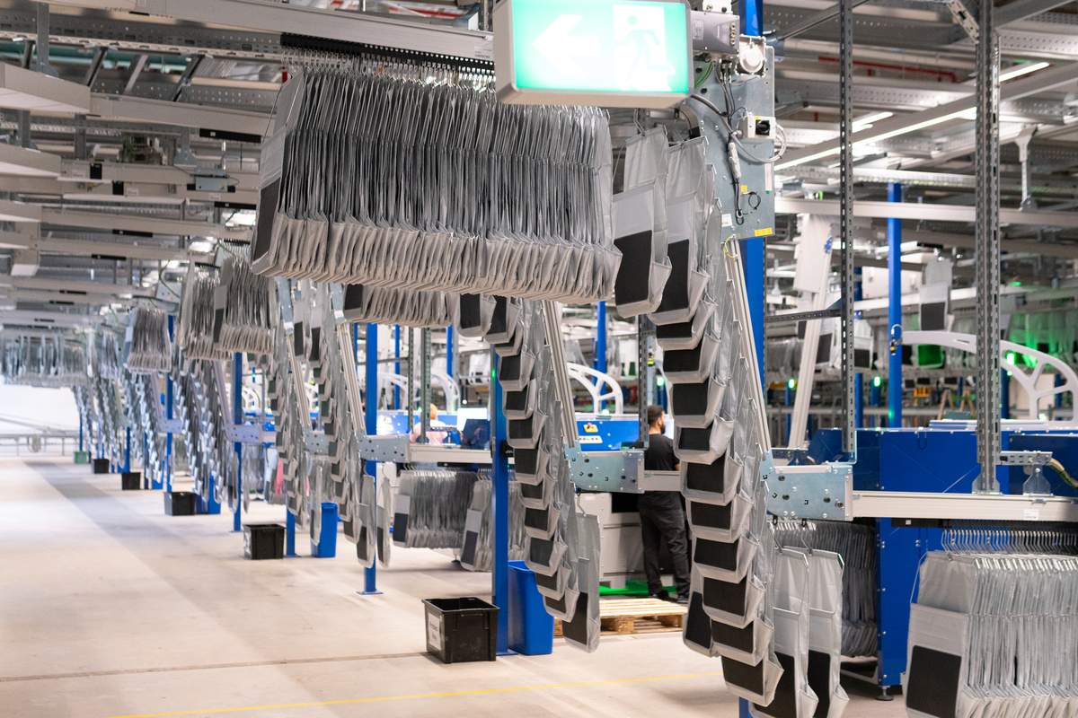 Dicht gestaute Taschen laufen im momox-Logistikzentrum Leipzig zu den Arbeitsstationen